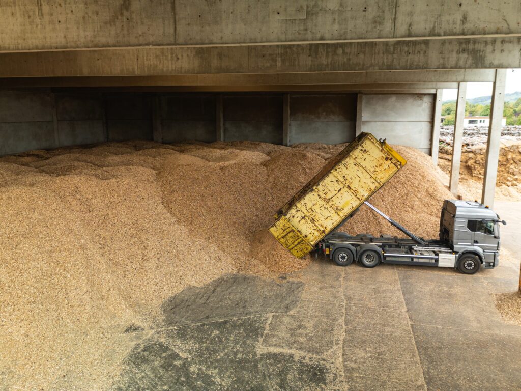 Large stockpiles of wood chips with several truck loads of deliveries per day