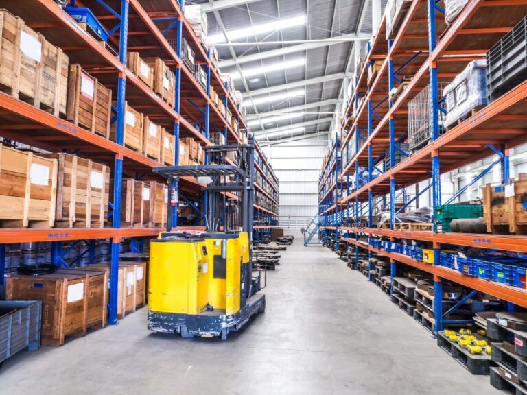 Forklift operating inside a warehouse, surrounded by stacked pallets and industrial shelving