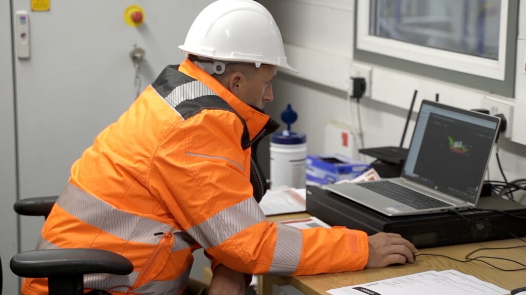 Person in a back office reviewing 3D point cloud data with stockpile measurement information for inventory analysis and planning.